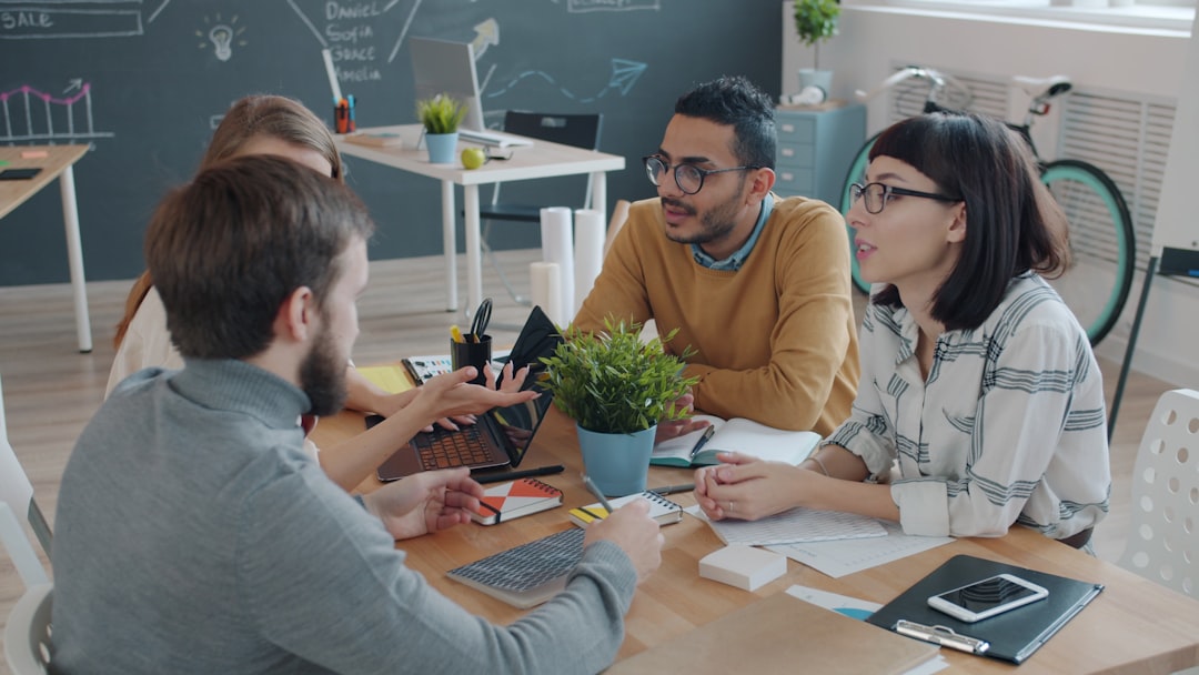 Multi-ethnic group of people are doing high-five talking and laughing in creative shared office during staff meeting. Communication and cooperation concept.